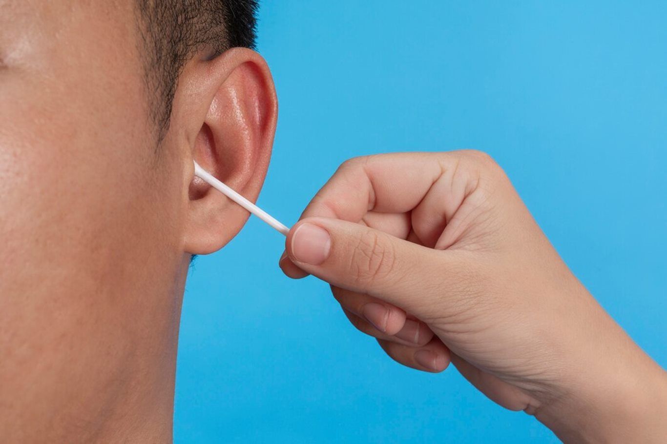 young-boy-is-ear-picking-with-cotton-swab-blue-wall-studio_1150-21915