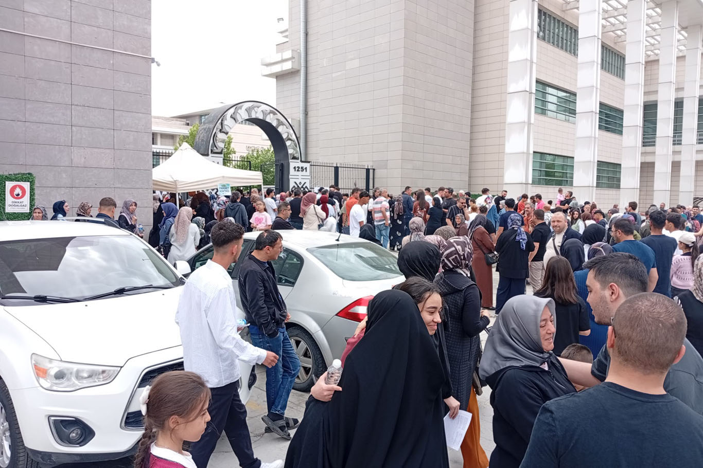 Sınav salonunda öğrenciler, kapıda dualarla bekleyen aileler